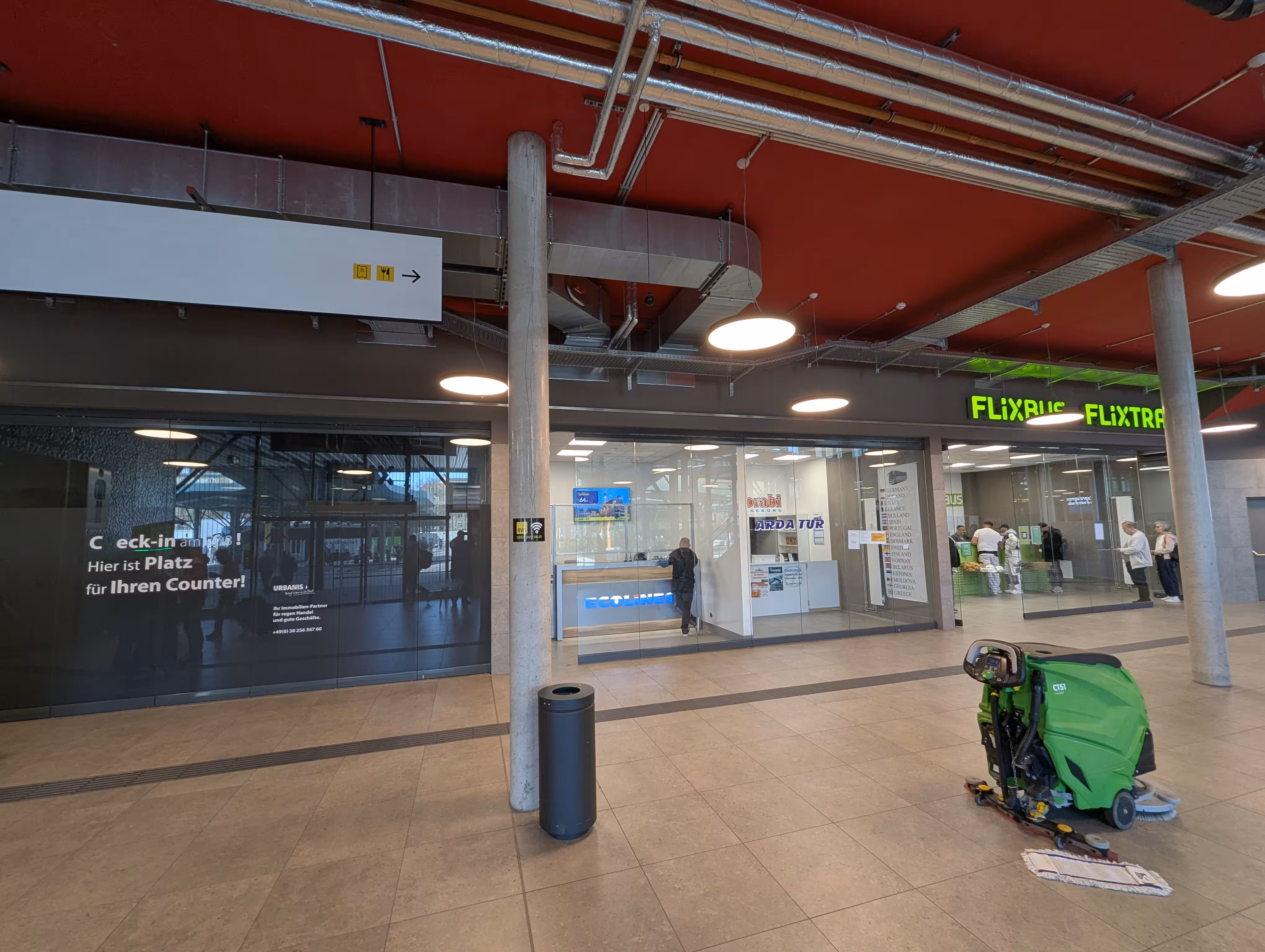 Eine Innenansicht der Wartehalle, im Hintergrund befinden sich zwei Ticketschalter, im Vordergrund steht ein Mülleimer